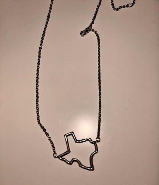 A silver necklace with a pendant in the shape of Texas