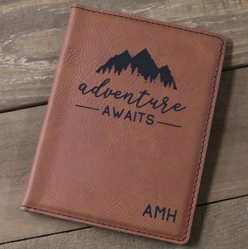A personalized leather passport cover with mountains and "Adventure Awaits"