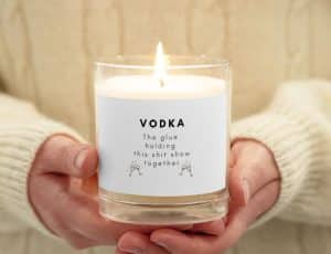 A candle with the label "Vodka, the glue that holds this shit show together" 